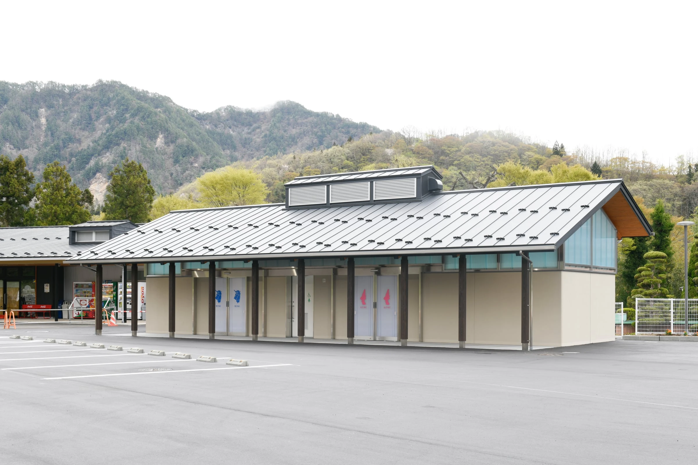 駐車場に建つ、庇が長く伸びたトイレ棟の外観
