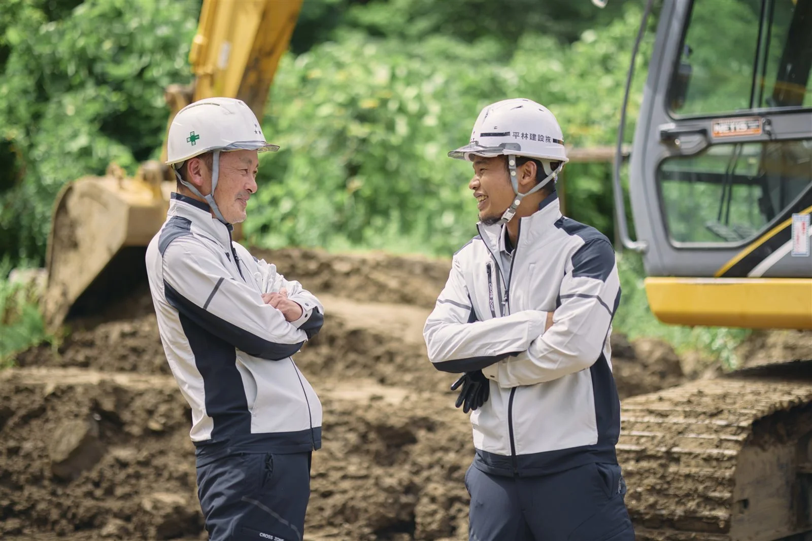 土の現場で笑い合う二人の社員