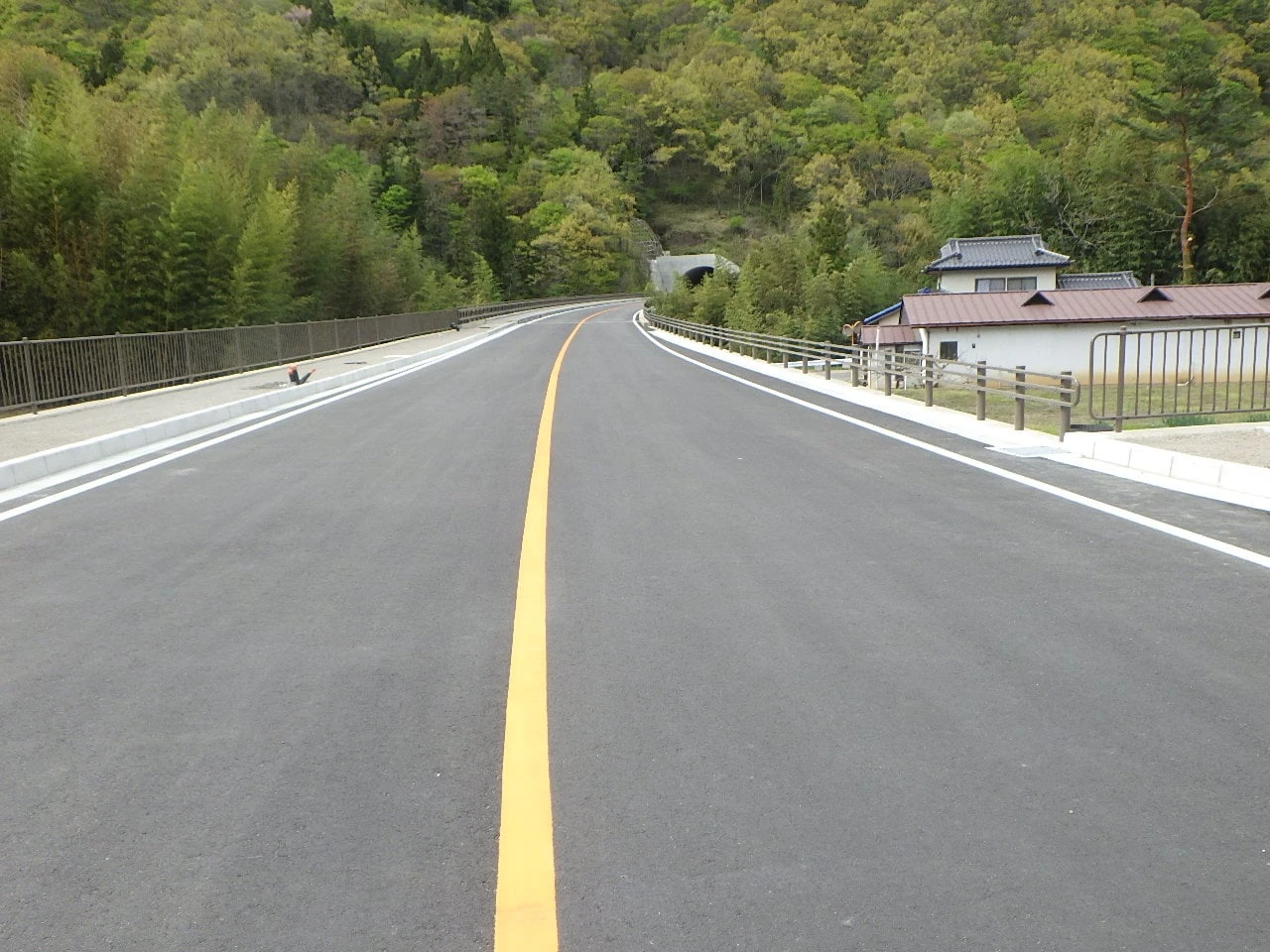 舗装を終えた2車線の道路。奥にトンネルの坑口が見える
