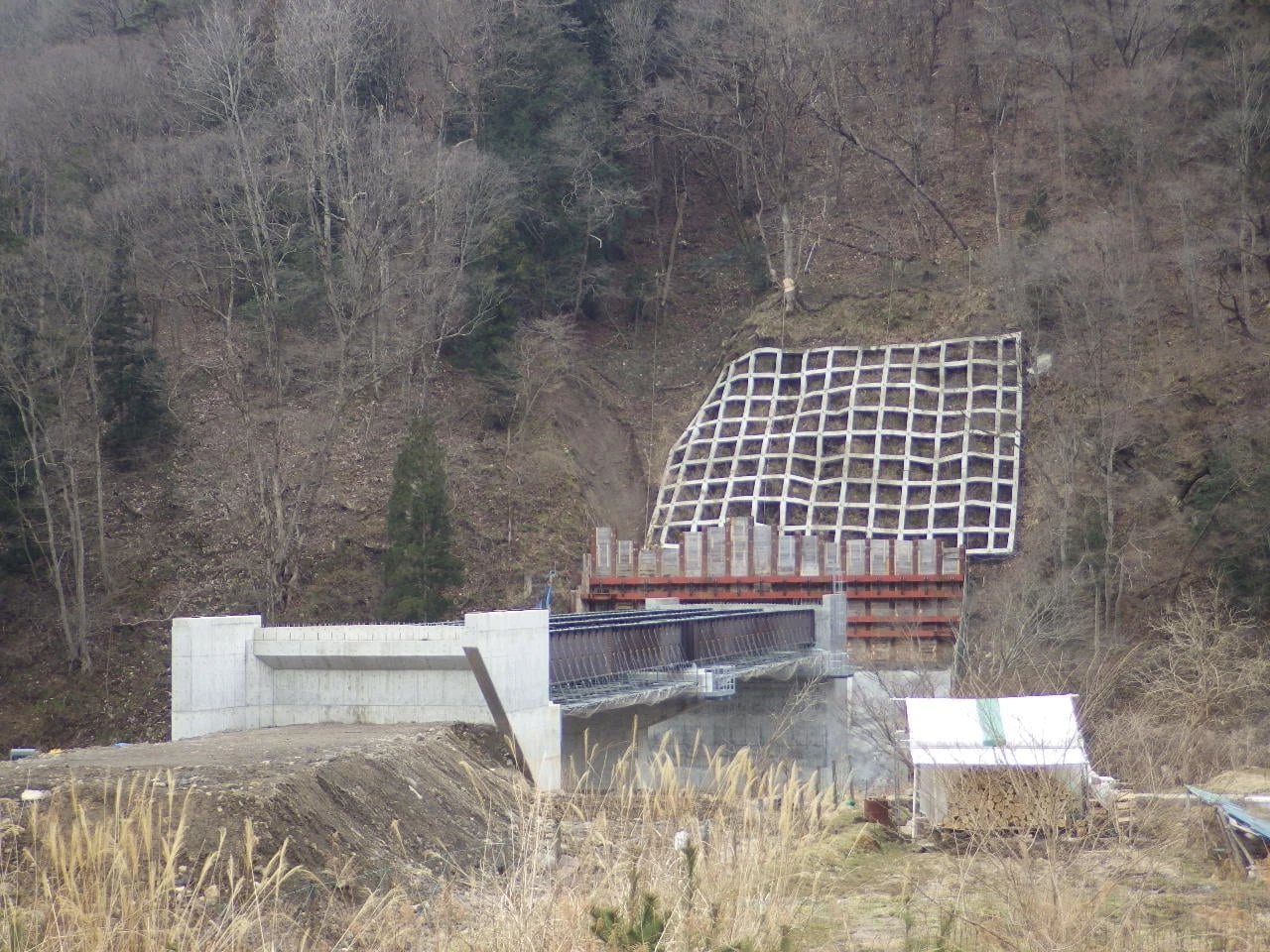 山肌に広がる法枠と、その下に据えた橋台