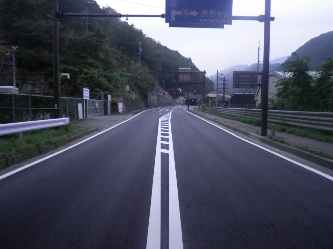 打ち替えた舗装と区画線。奥に国道の案内標識とトンネルが見える