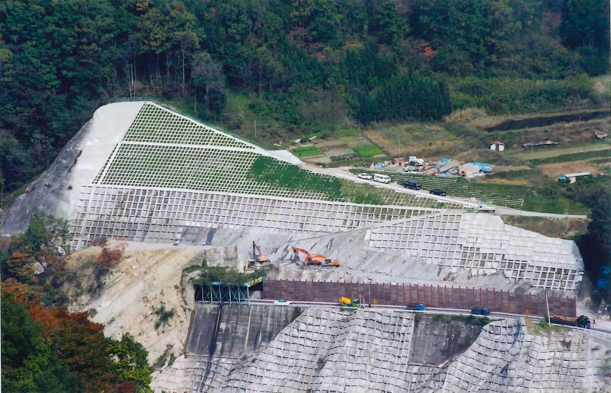 当時の空撮写真。国道沿いの山肌一面に、段状の法面工と法枠が施されている