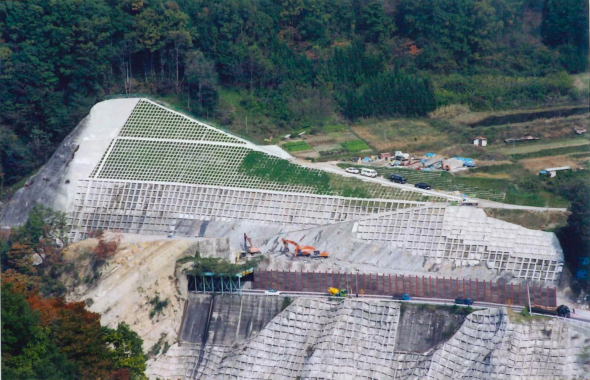 当時の空撮写真。国道沿いの山肌一面に、段状の法面工と法枠が施されている