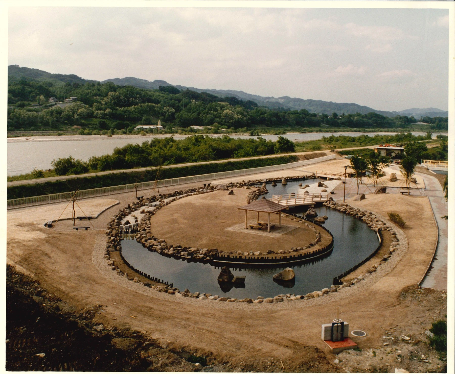 当時の写真。造成を終えた公園の池と東屋、川沿いの園路
