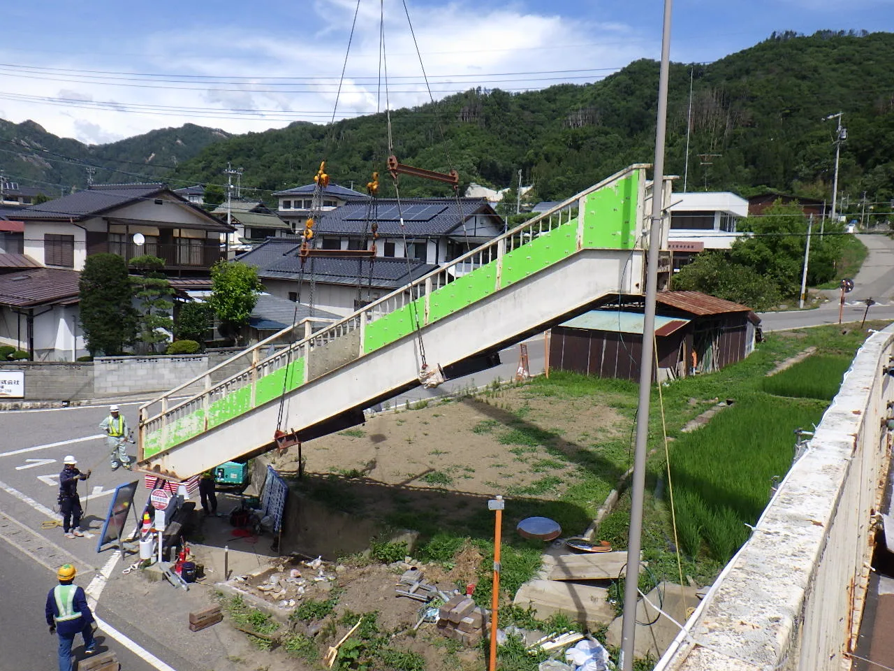 クレーンで歩道橋の斜路を吊り上げ、据え付ける作業