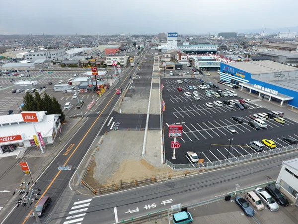 高い位置から見た、拡幅中の幹線道路と沿道の店舗・駐車場