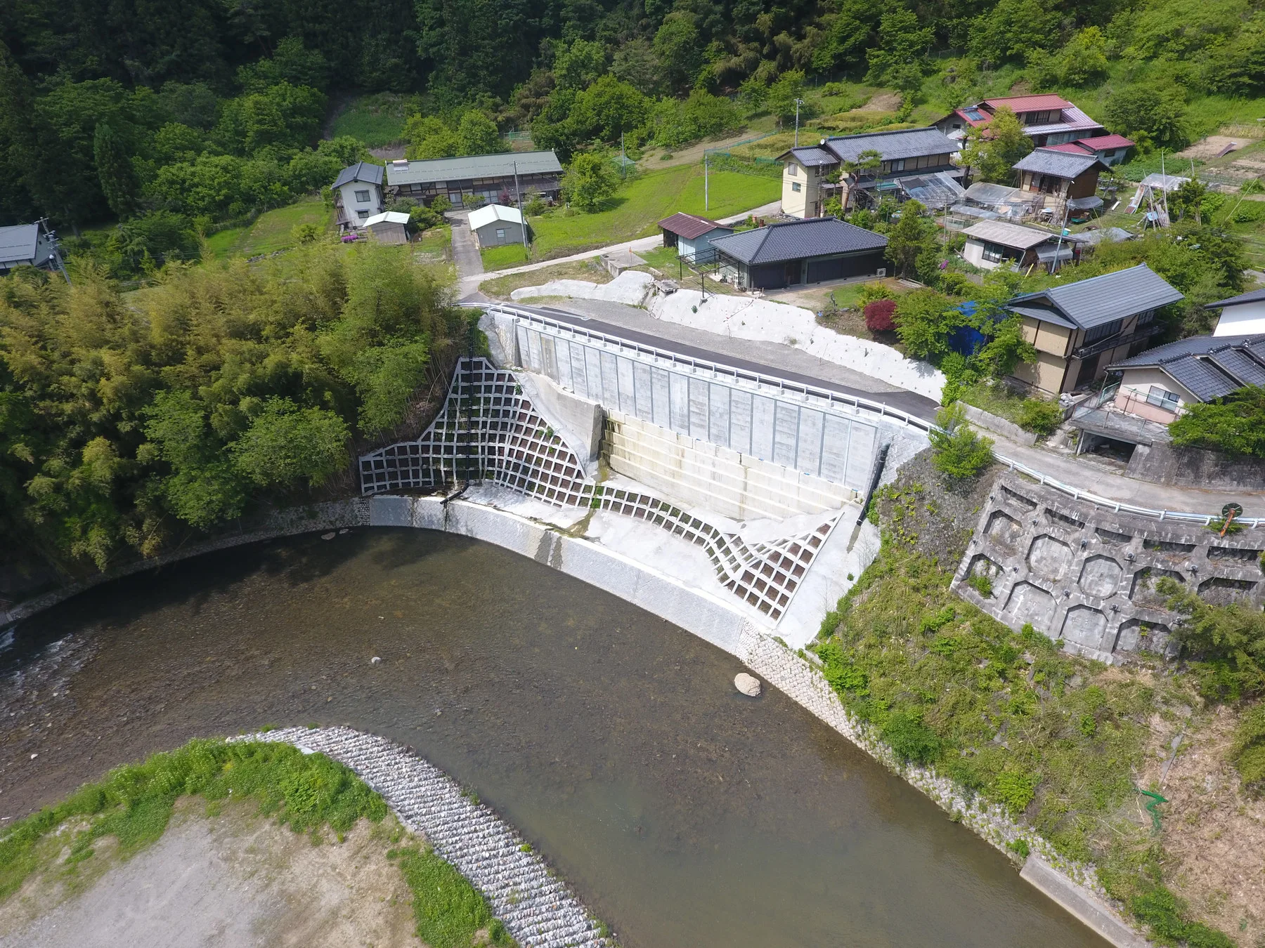 上空から見た、川沿いに築いたブロック張りの護岸と、その上に並ぶ集落