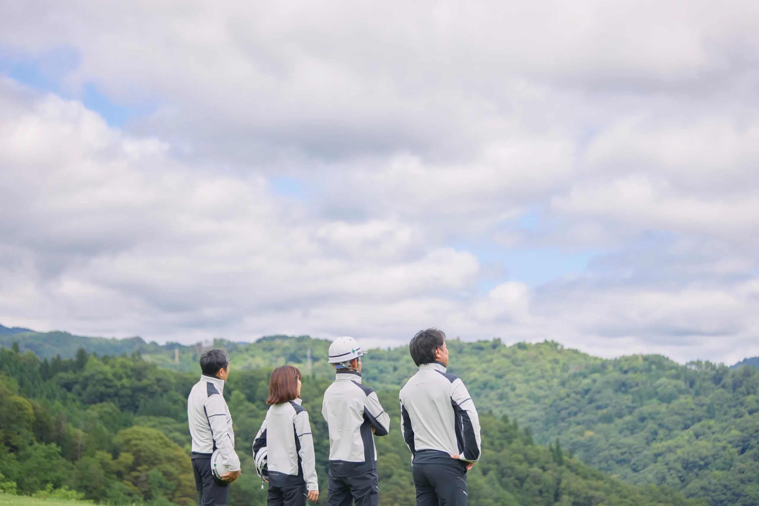 丘の上で談笑する4人の社員