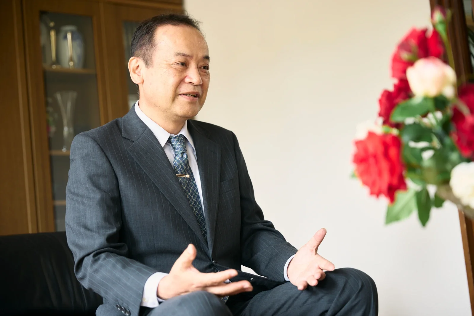 社名ロゴを背にして立つ専務取締役