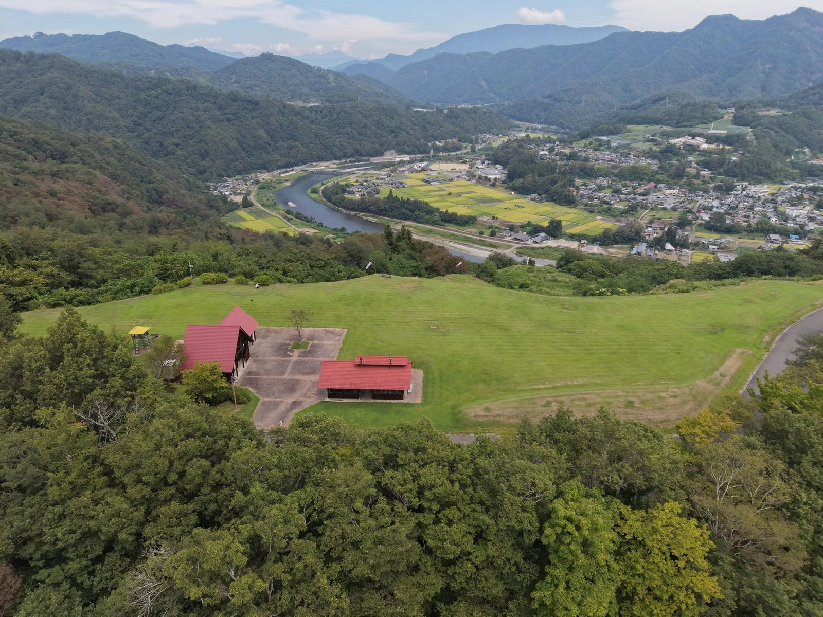 広場の先に見下ろす、川沿いの集落と実りを迎えた田畑