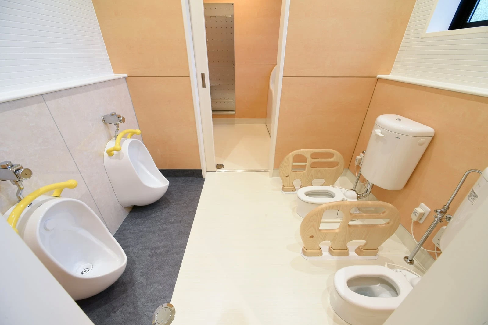 子ども用の小さな便器と補助便座が並ぶトイレ