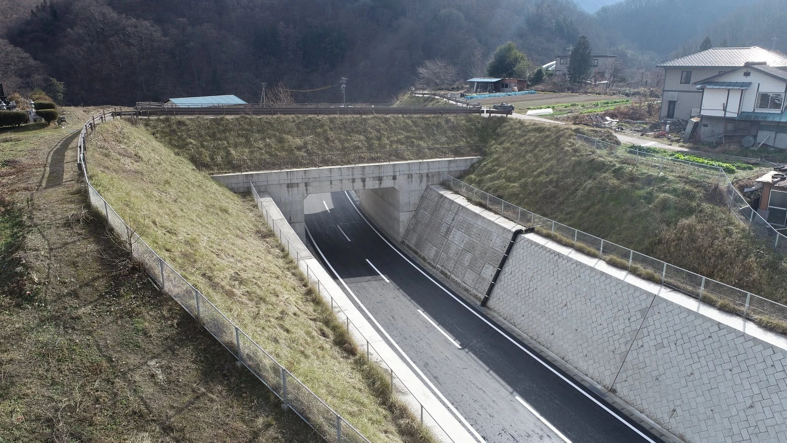 上空から見た、コンクリート擁壁と法面のあいだを通る舗装道路