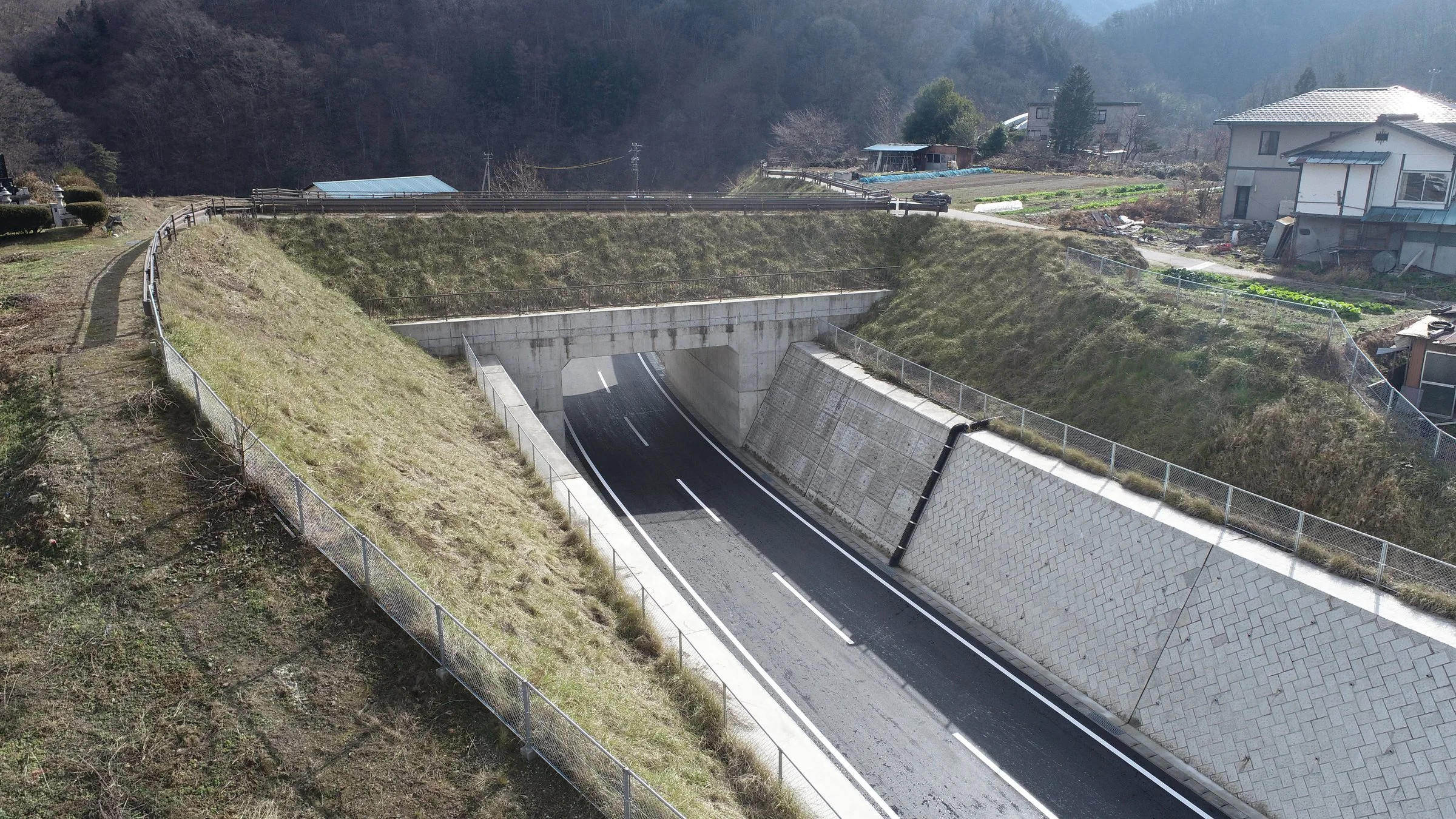 上空から見た、コンクリート擁壁と法面のあいだを通る舗装道路