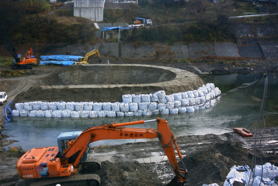 川の中に大型土のうで仮締切を築き、重機が作業する様子