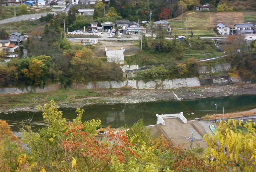 紅葉した対岸の集落と、川べりに据えられた橋台