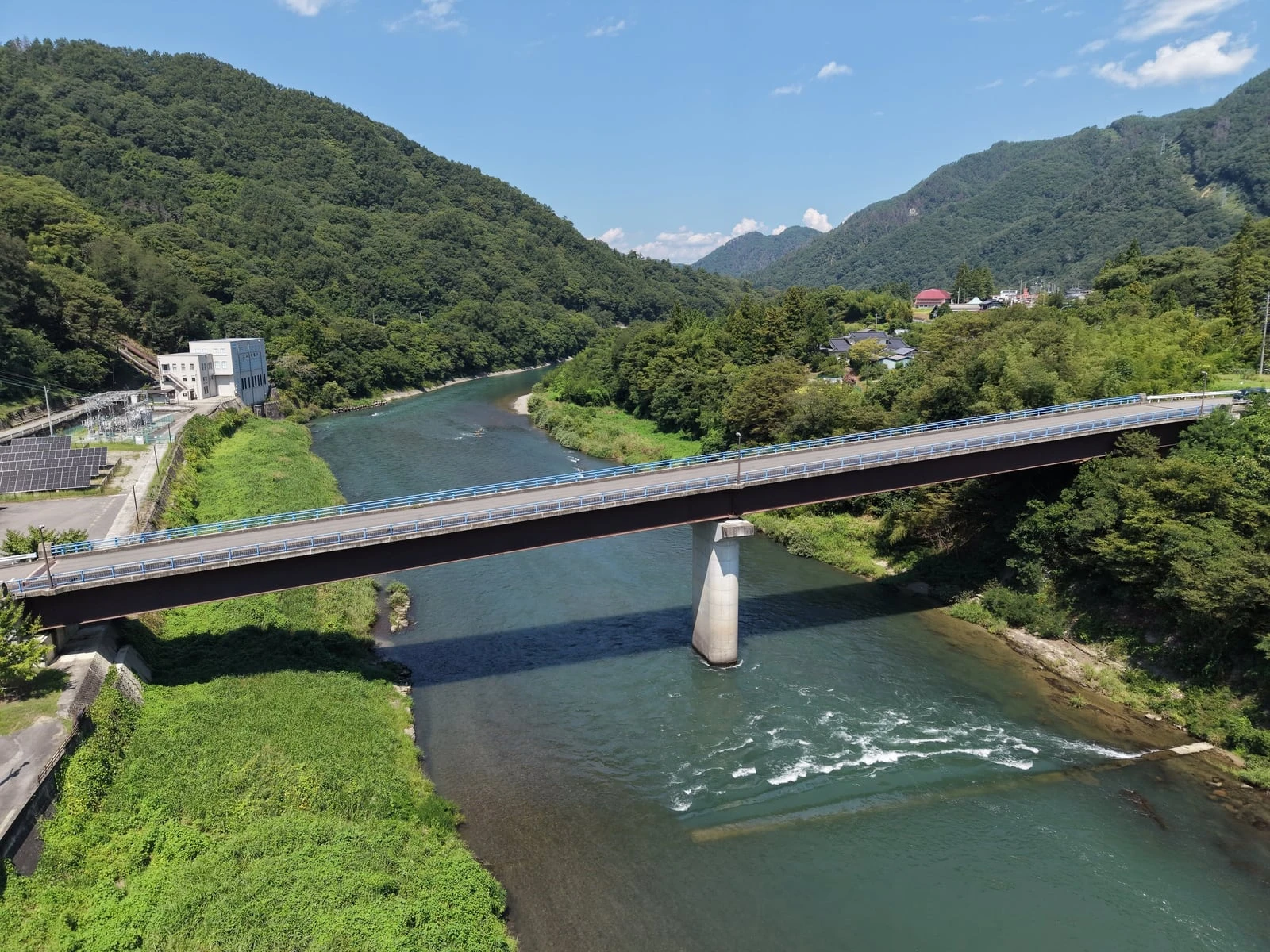 上空から見た、川を渡る完成した橋と一本の橋脚