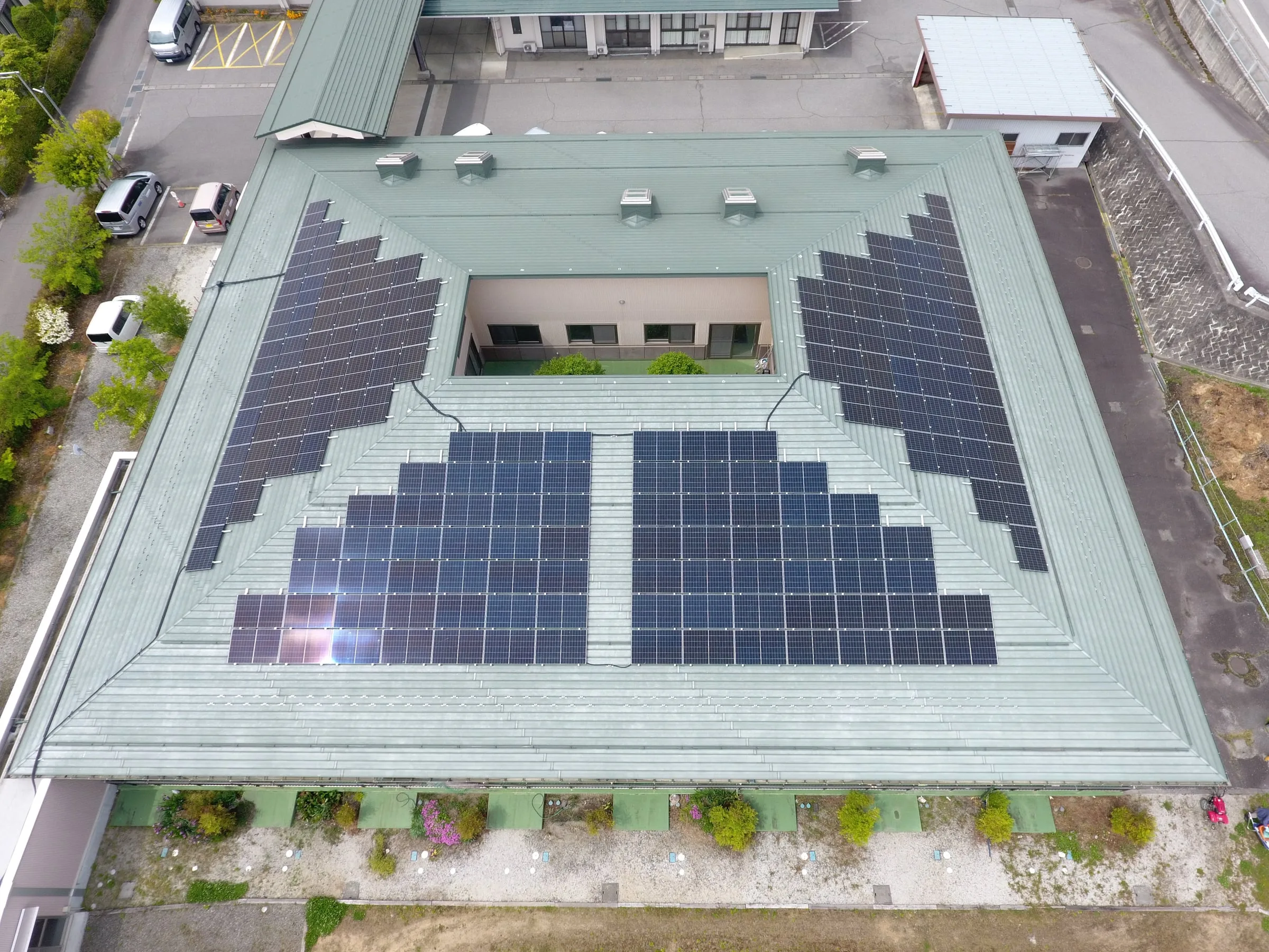 中庭を囲む建物の屋根に、左右対称に並べた太陽光パネル