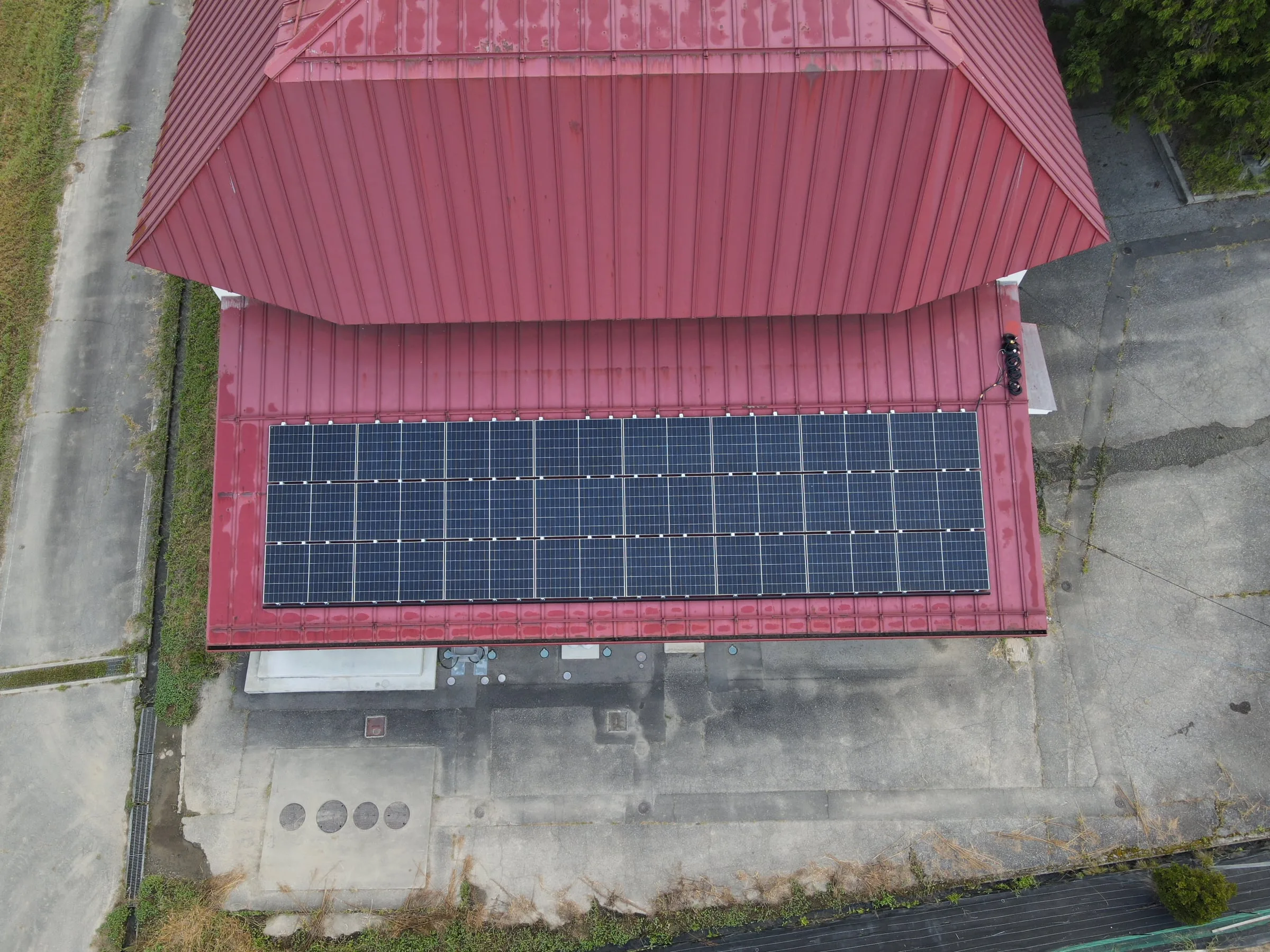赤い屋根の建物と、その下屋に並べた太陽光パネル
