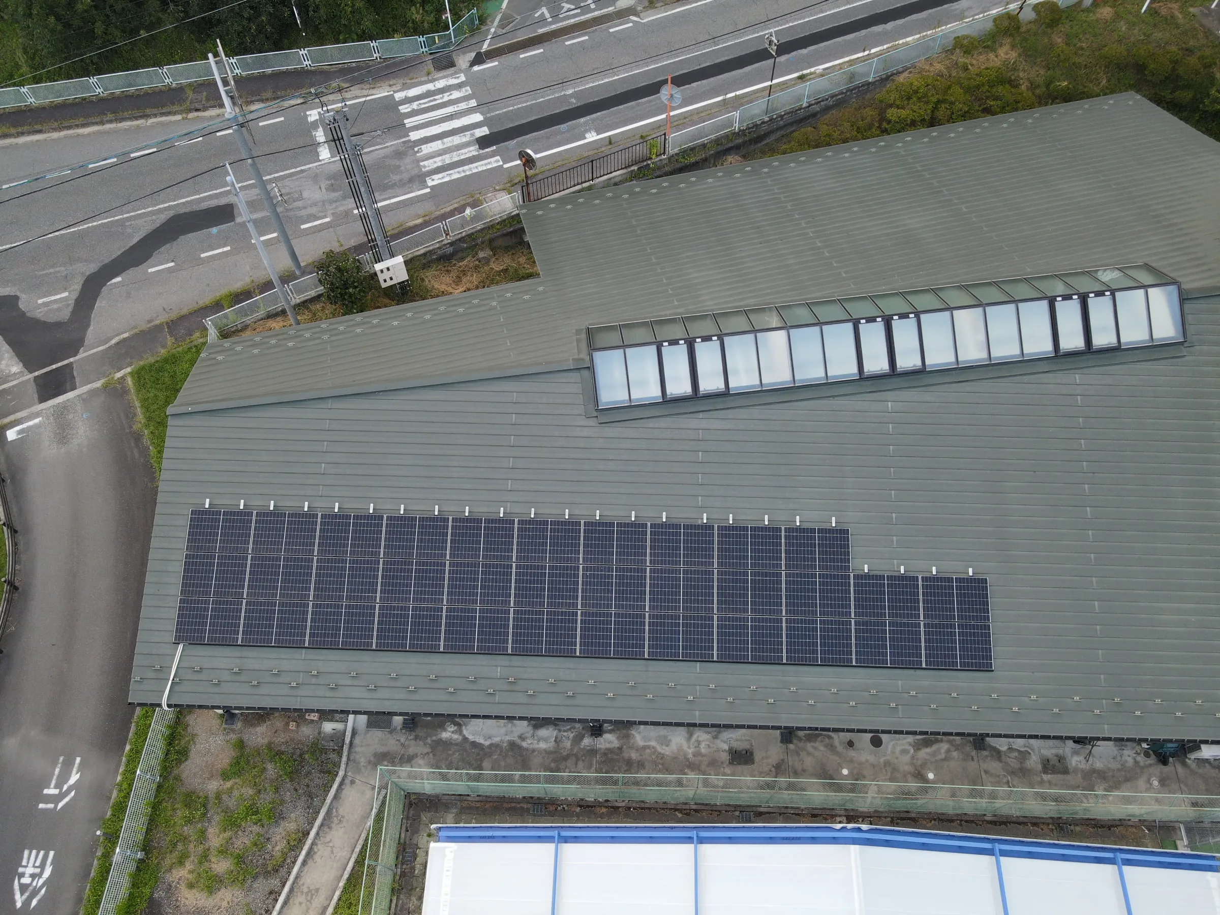 天窓のある建物の屋根に、軒に沿って並ぶ太陽光パネル