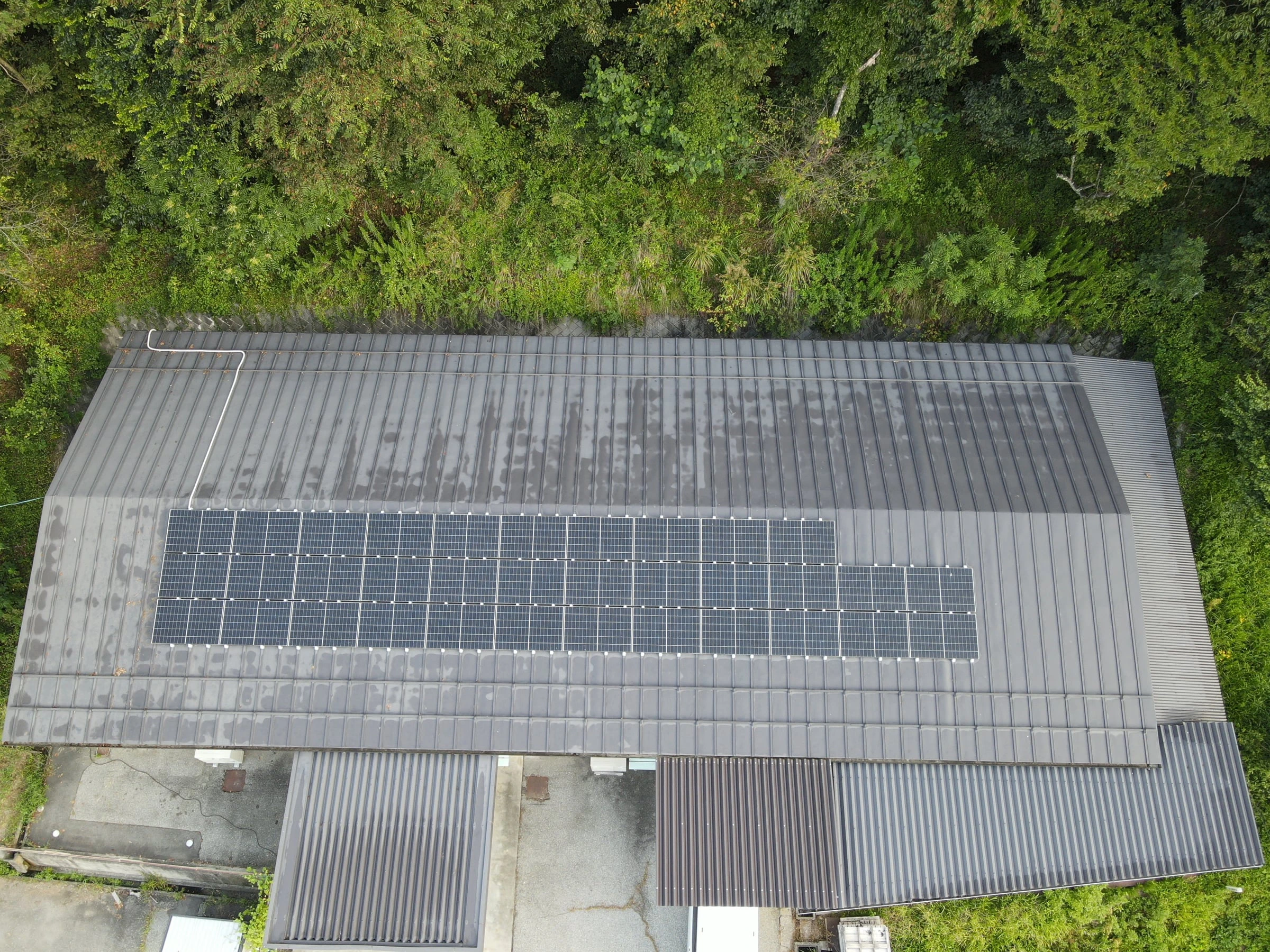 横長の建物の屋根の中央に並ぶ太陽光パネル