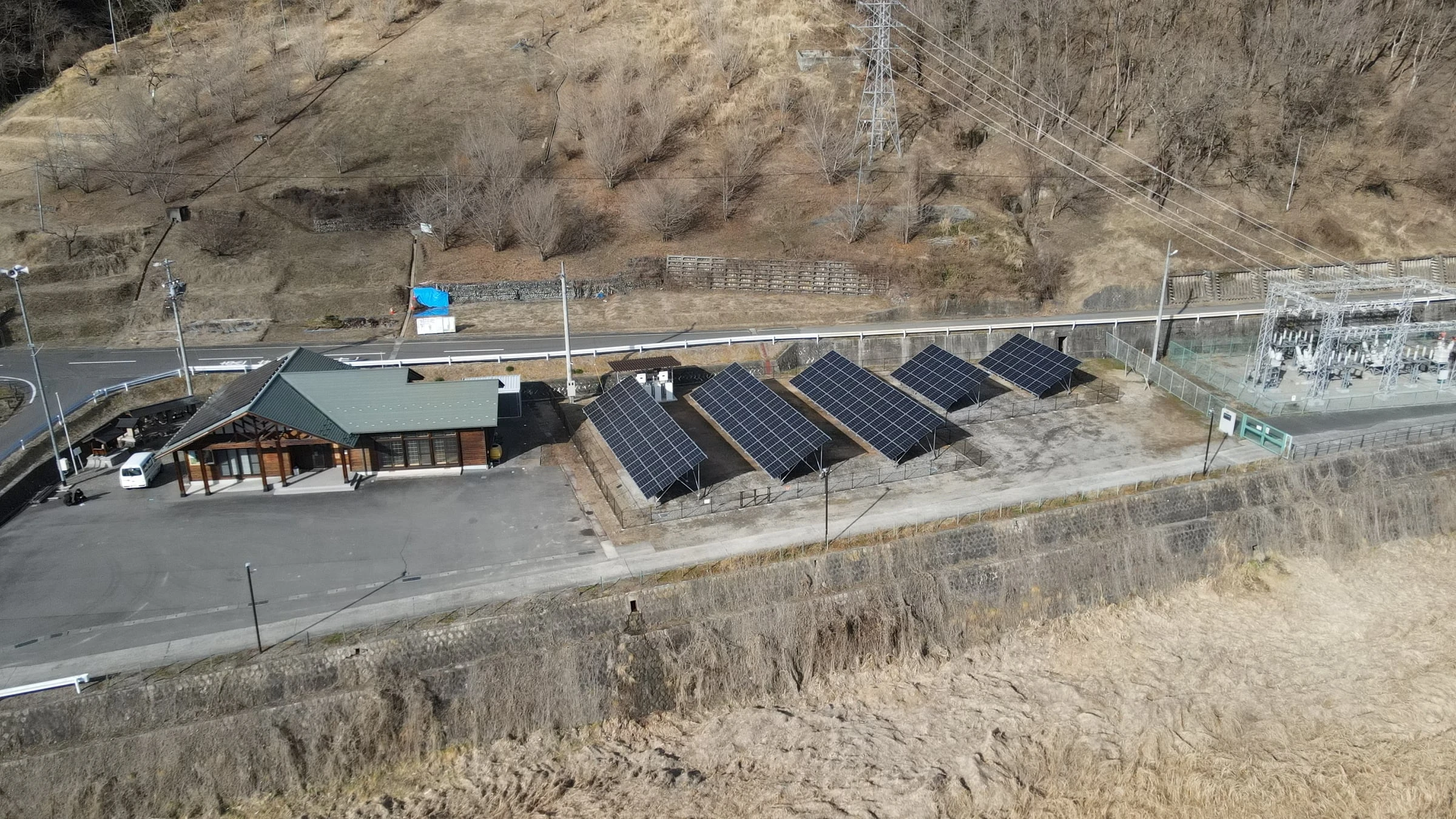施設の脇の敷地に据えた4連の太陽光パネルと、奥の変電設備