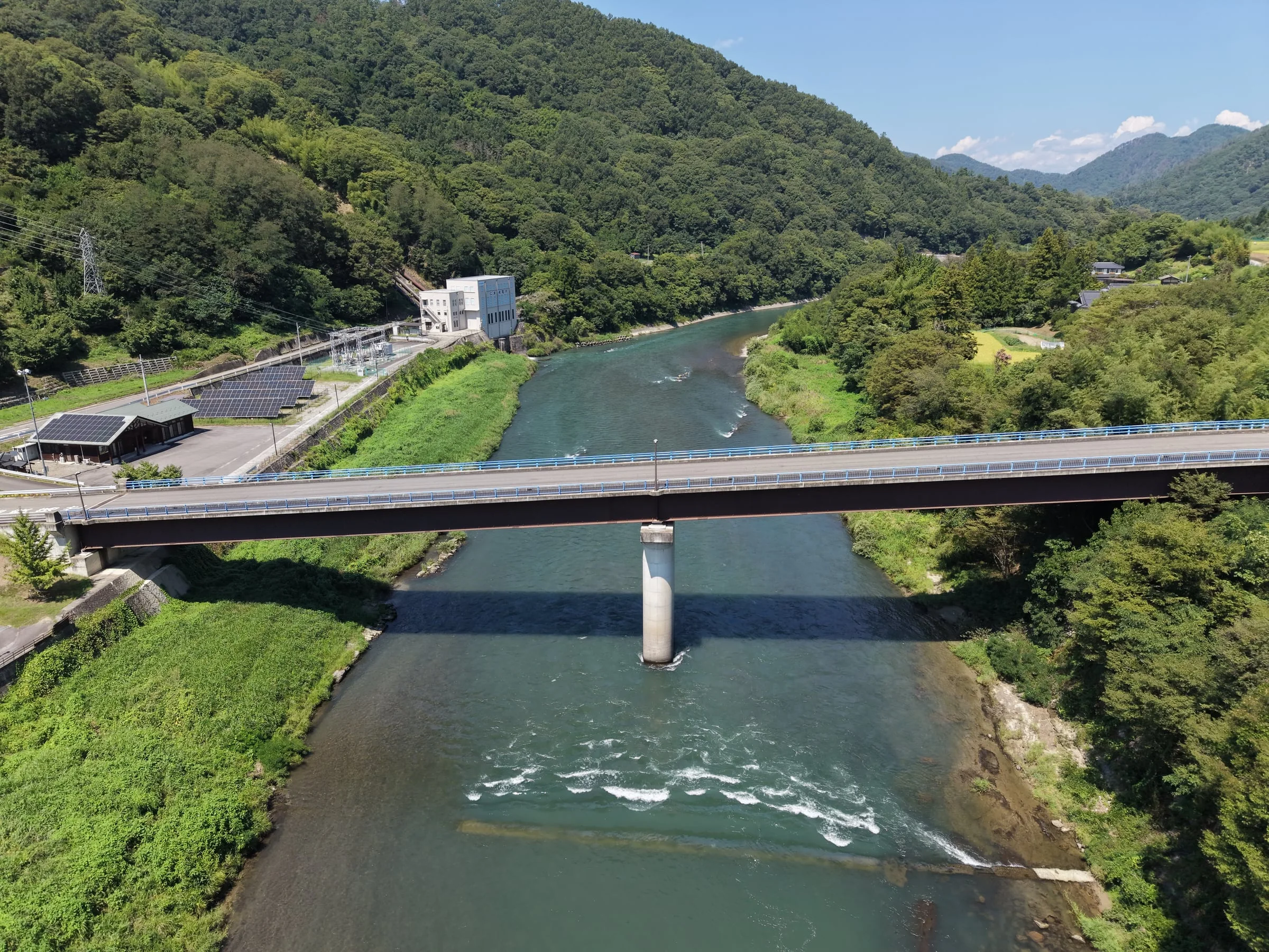 山あいの川に架かる橋を上空から見た様子。中央に一本の橋脚が立つ